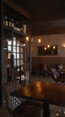 Boş bir restoranın içinde ahşap masalar, deri sandalyeler, loş ışıklar ve rahat bir ortam sergileniyor..