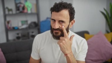 Evde şüpheli orta yaşlı bir adam var. Gözünü dikip jestini izliyor, beyaz tişört giyiyor.