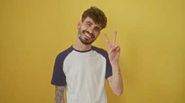 Neşeli genç İspanyol adam zaferini ifade ediyor, gülümsüyor ve göz kırpıyor, parlak sarı bir arka planda tek başına duruyor.