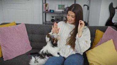Rahat bir süveter içinde gülümseyen bir kadın modern bir oturma odasında teriyeriyle kaliteli vakit geçirmekten zevk alır..