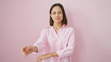 Gömlekli güzel İspanyol kadın kendine güvenen bir poz veriyor. Kameraya çapraz kollarla gülümsüyor, elleri çenesinde, pembe izole edilmiş arka planda pozitif düşünüyor..