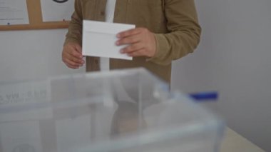 İspanyol bir adam, kapalı bir seçim salonunda demokratik bir süreci eylem halinde göstererek oy veriyor..