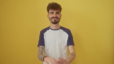 Neşeli, genç, Latin asıllı, dimdik ayakta duran, parmaklarıyla on numarayı gösteren, yukarıyı gösteren adam. İzole edilmiş sarı arka planda neşeyle gülümsüyor.