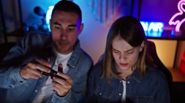 Bir adam ve bir kadın, gece renkli neon ışıklı bir odada oynamaya odaklandılar. Heyecan ve konsantrasyonlarını ifade ediyorlardı..