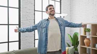 Parlak, modern bir oturma odasında sakallı, mutlu bir İspanyol adam.