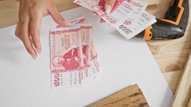Elleri İzlanda Krona banknotlarını yakınındaki bir marangozluk masasının üzerinde tutuyor, para birimi atölyesi tasarruf kavramları.