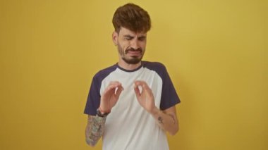 İğrençlik ifadesi takınan, tiksinmiş ve korkmuş genç bir adam tiksinti reaksiyonu yüzünden tiksinti ifadesi takınıyor. Eller izole edilmiş sarı arka planda.