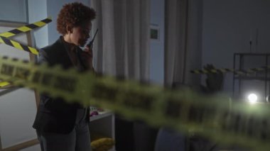 Bir kadın dedektif gece bir evin içini araştırıyor, el feneri ve telsizle suç mahalli bandı arasında..