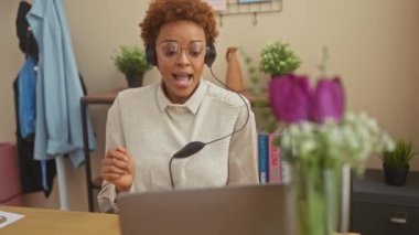 Neşeli bir Afrikalı Amerikalı kadın evinde dans ederken ve dizüstü bilgisayarı üzerinde çalışırken müzik dinlemekten zevk alıyor..