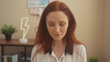 Kızıl saçlı ve sıcak bir gülümsemesi olan güzel, genç bir kadın evinde rahat bir şekilde poz veriyor, arkadaşça ve cana yakın..