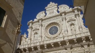 Santa Croce Bazilikası 'nın karmaşık cephesi. Açık mavi gökyüzü altında şaşırtıcı barok mimari sergileniyor..