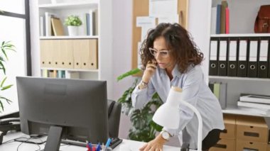 Parlak ofis ortamında çalışan ve telefonla konuşan olgun bir kadın.