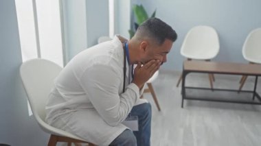 Klinik bekleme odasında rozeti olan stresli bir İspanyol..