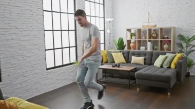 Dinamik bir genç adam modern, parlak oturma odasında tek başına dans ediyor, enerji ve yaşam tarzı sergiliyor..