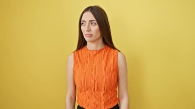 Yakından, kendinden emin ve doğal olarak İspanyol kadının sarı stüdyo içinde kolsuz bir tişört giyip kameraya güvenmesi.