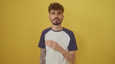 Genç, yakışıklı İspanyol bir adam izole edilmiş sarı bir arka plana karşı duruyor, kameraya sevgi ve ifadeyle öpücük yolluyor, sevimli ve seksi görünüyor.