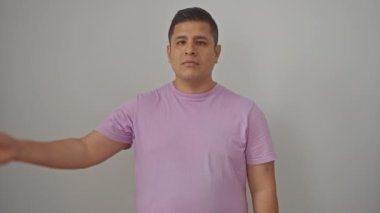 Beyaz arka planda tek başına duran genç İspanyol bir adam. Yüzü elle örtülmüş. Şok olmuş parmaklarının arasından bakıyor.