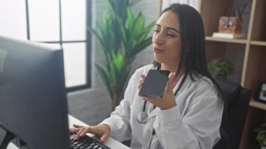 Neşeli bir İspanyol kadın doktor modern bir klinikte sesli mesaj gönderiyor.