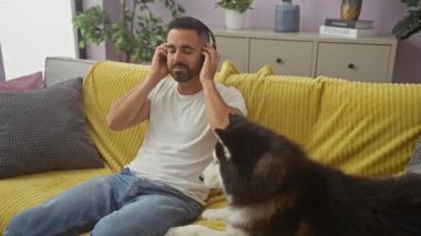 İspanyol adam kulaklıklı müzikten hoşlanıyor ve rahat oturma odasında kabuklu hayvan besliyor.