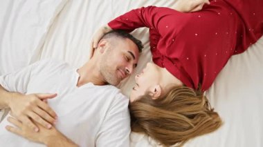 Birbirine aşık çift, sıcak bir yatak odasında, beyaz bir yatakta uzanıyor. Aile ortamında sevgi ve bağlılık gösteriyorlar..