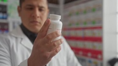 Odaklanmış İspanyol bir adam eczanede bir ilaç şişesini inceleyip arka planda raflar dolusu ürünü inceliyor..