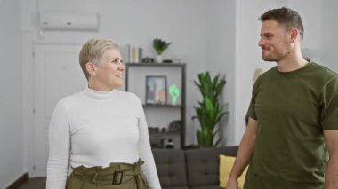 Bir erkek ve kadın, samimi, modern bir oturma odasında şefkat ve kucaklaşmayı paylaşır..