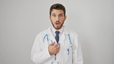 Ağzı açık, steteskop takmış, şüpheci, genç İspanyol bir adam beyaz soyutlanmış arka planda alaycı bir ifade sergiliyor..