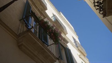 Güzel bir balkon. Çiçeklerle süslü bir bina. Açık mavi gökyüzüne karşı gösterişli, puglia, İtalya klasik mimarisi..