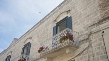 Materya, bazilika, İtalya 'daki geleneksel taş ev cephesinin açık hava görüntüsü. Mavi panjurlar, süslü balkonlar ve canlı kırmızı çiçekler..