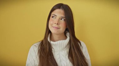 Süveter giyen, kendine güvenen, sarı bir duvara yaslanmış, düşüncelere dalmış gülümseyen, güler yüzlü, güveni ve ilgiyi ifade eden neşeli İspanyol bir kadın..