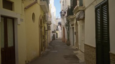 Gelibolu, puglia 'daki dar eski cadde, açık mavi gökyüzünün altında pastel renkli binalar ve balkonlarla dolu..  
