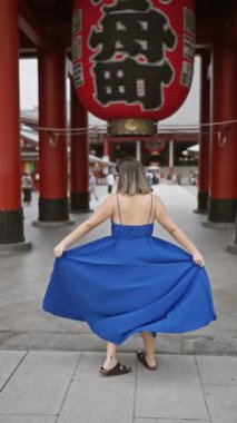 Neşeli İspanyol kadın, Senso ji Tapınağı 'nın Tokyo' daki görkemli mimarisi arasında güzel elbiseler içinde neşeyle dans ediyor. Japonya 'yı gezerken, şehir maceralarında mutluluk saçar..