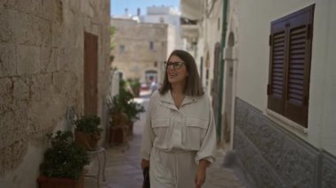Genç bir İspanyol kadın güvenli bir şekilde polignano 'nun büyüleyici taş sokaklarında yürüyor Puglia, İtalya' da güzel bir günün tadını çıkarıyor..