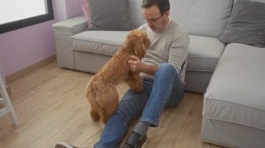 Orta yaşlı bir adam kanişiyle samimi bir oturma odası ortamında etkileşime girer. Arkadaşlığı ve rahatlığı simgeler..