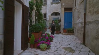 Genç bir İspanyol kadın polignano 'nun resimli taş caddelerinde yürüyor bir kısrak, puglia, İtalya, çerçeveli saksı çiçekleri ve tarihi mimari.