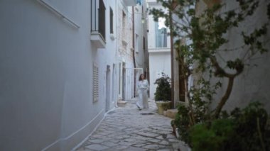 Genç İspanyol kadın polignano 'nun taş caddelerinde yürüyor kısrak, puglia, İtalya.