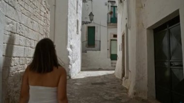 Beyaz elbiseli genç bir İspanyol kadın, eski güzel bir kasaba olan Ostuni 'yi, Puglia' yı, İtalya 'yı keşfediyor..
