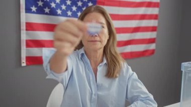 Orta yaşlı bir kadın, arka planda Amerikan bayrağı olan ve seçimlere katılımımızı sembolize eden bir çıkartma gösteriyordu.