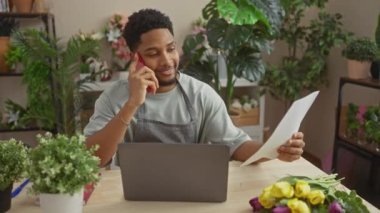 Çiçekçide telefonla konuşurken belgeyi okuyan Afrikalı Amerikalı bir adam.