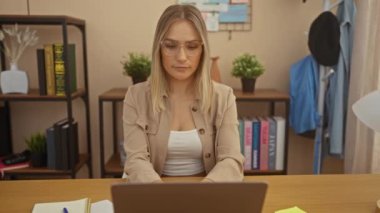 Evdeki ofis ortamında dizüstü bilgisayarda çalışan güzel beyaz bir kadın hapşırıyor gibi görünürken etrafı defterler, bitkiler ve çeşitli eşyalarla dolu bir kitaplık ile çevrili..