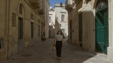 Genç İspanyol kadın ders veriyor, puglia, İtalya dar tarihi sokaklarda kırsal mimariyle yürüyor..