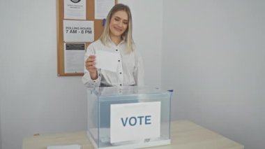 Sarışın genç bir kadın kapalı bir sandıkta oy kullanırken oy verme eylemini ve oy kullanma odasının atmosferini vurguladı..