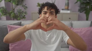 Genç İspanyol adam, elleri içeride kalp şeklinde yapıyor.