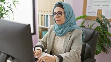 Ofiste bilgisayarının başında çalışırken omuz ağrısı çeken profesyonel bir kadın..