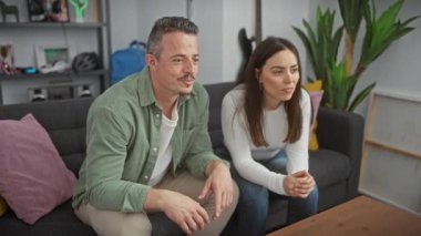 Bir erkek ve kadın, modern dekorasyonla sıcak bir oturma odasında birlikte kutluyor, ilişkilerinde neşe ve beraberliği ifade ediyorlar..