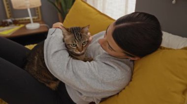 Sıcak bir yatak odasında rahat bir yatakta kedi yavrusu tutan genç bir İspanyol kadın evcil hayvan ve sahibi arasındaki bağın altını çiziyor..
