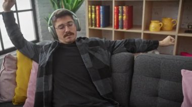 İspanyol adam evde kulaklıklarla dinleniyor.
