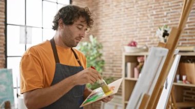 Parlak bir sanat stüdyosundaki tuvale odaklanmış İspanyol bir adam.