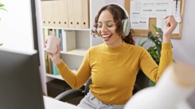 Neşeli bir kadın ofisinde müzik dinlemekten, elinde kupayla ve kulaklıkla dans etmekten hoşlanır..