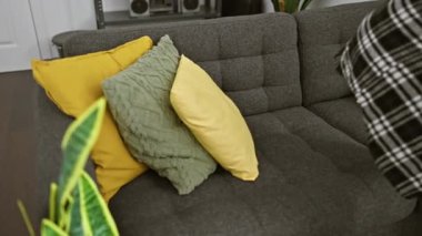 Yaşlı adam rahat bir evde renkli yastıkları olan bir koltukta dinleniyor..